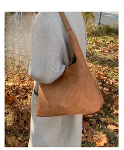 Detailed view of a brown suede tote bag carried by a model in an autumn outdoor setting