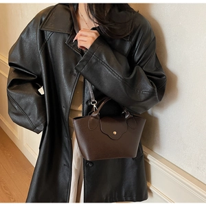 Detail of dark brown lychee leather bucket bag featuring a gold metal clasp and long strap