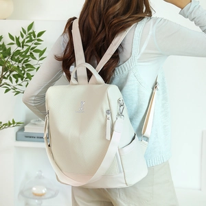Rear view of ivory travel backpack showing anti-theft zipper and woven shoulder straps