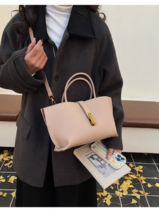 Detail of light pink pebble leather tote bag with gold metal lock on casual street style outfit