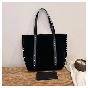 Detail view of large suede tote bag with silver studs and a smartphone for size reference