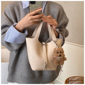 Detalle de bolso cubo de cuero crema con un encantador colgante de oso de peluche