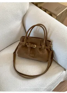Detail of caramel brown suede tote bag featuring a decorative belt buckle and logo