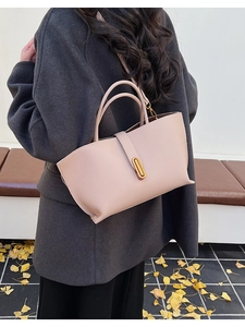 Detail of pink lychee leather shoulder bag with gold metal buckle on autumn background