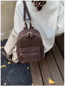Détail d'un mini sac à dos marron foncé avec coutures contrastées dans un décor d'automne