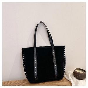 Close-up of black suede tote bag with silver studs on a wooden table display