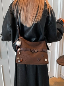 Brown suede tote bag with bow and star details worn by a model in leather jacket