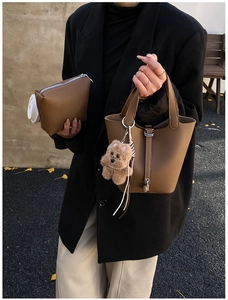 Detalle de bolso cubo en cuero granulado con colgante de oso y estuche interior