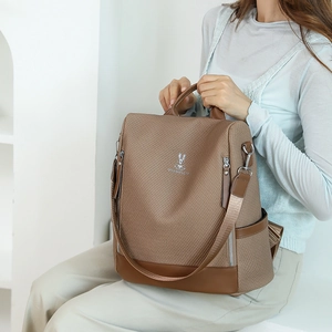 Close-up of brown textured leather backpack with silver rabbit logo and metal hardware