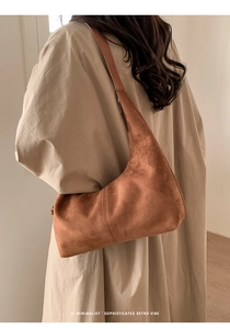 Detail of caramel brown suede hobo bag showing vertical stitching and matte texture