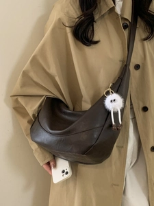Brown semi-circle crossbody bag with vintage leather texture and monster plush charm