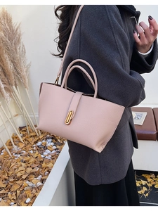 Detail of dusty rose bucket bag with litchi texture leather and gold buckle closure
