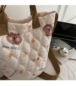 Detail of quilted nylon bag showing teddy bear patterns with cotton carry handles