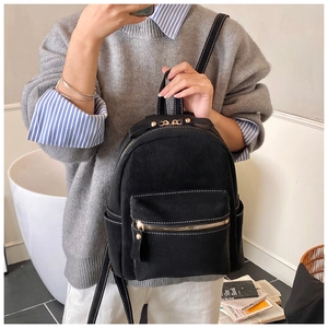 Detail of mini black suede backpack showing contrast white stitching and gold hardware
