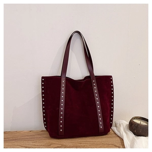 Detailed macro of burgundy suede tote bag featuring metallic silver stud accents