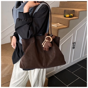Detail view of large dark brown matte tote bag with cute bear charm on shoulder strap