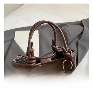 Détail du sac à main en cuir marron avec base léopard et poignée à nœud distinctive