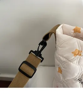 Detail of durable black plastic detachable hook on beige quilted bag with star pattern