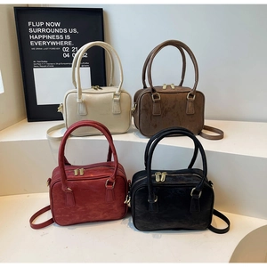 Detail view of retro suede Boston bags in four colors with gold zippers and hardware