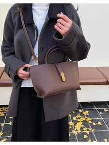 Detail of vintage brown leather bucket bag with gold hardware shown in an autumn setting