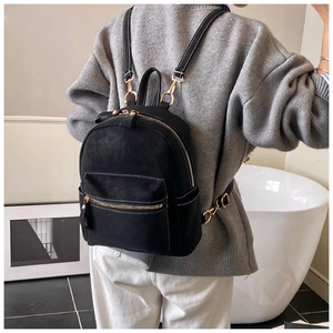 Detail of black suede mini backpack featuring gold hardware and white contrast stitching