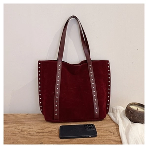 Detail showing burgundy suede tote bag with silver studs and a phone for size comparison