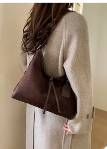 Détail d'un sac porté épaule en daim marron foncé avec fine bandoulière en cuir
