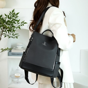 Detail of black woven texture backpack with silver metallic logo and zipper accents