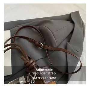 Détail de la bandoulière réglable en cuir marron foncé avec boucle et nœud décoratif