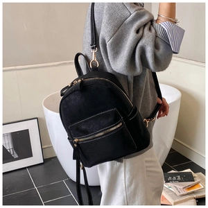 Détail du mini sac à dos en cuir noir avec fermetures dorées et coutures blanches contrastées
