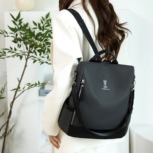 Deep gray textured backpack with white rabbit pattern shown on model in a bright home setting