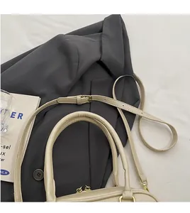 Detail of adjustable long shoulder strap and golden metal buckle on beige suede bag