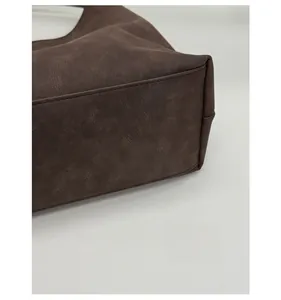 Close-up of reinforced bottom stitching and textured dark brown faux leather tote bag
