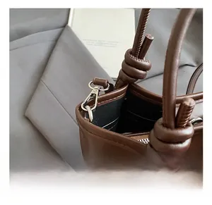Détail du fermoir en métal et de l'anse en cuir noué sur le sac seau léopard