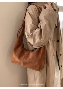 Detail of a brown suede hobo bag with a minimalist half-moon shape and a top zipper