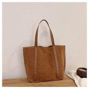 Detail view of large brown suede tote bag with silver rivet studs and twin handles