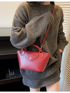 Red lychee grain leather bucket bag with top handle and gold clasp crossbody view