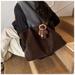 Detail of dark brown matte tote bag with cute knitted bear charm on shoulder strap