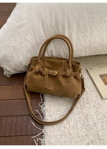 Detailed view of brown faux leather tote with decorative buckle strap and fashion label