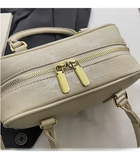 Detailed close-up of smooth dual golden zippers and textured beige boston handbag fabric