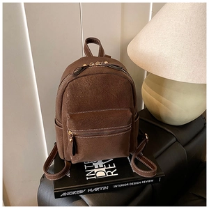 Gros plan d'un sac à dos vintage en cuir marron avec surpiqûres blanches sur livres