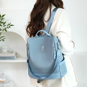 Lifestyle view of light blue backpack featuring woven texture and rabbit logo detail
