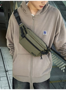 Detail of army green checkered chest bag with durable strap and buckle on model