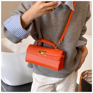 Nahaufnahme der orangen geflochtenen quadratischen Tasche mit goldenem Schloss
