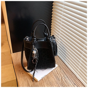 Détail du sac seau à imprimé léopard noir avec doubles poignées et breloque élégante