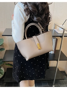 Detail of grey lychee leather tote bag with gold metal clasp and elegant stitching