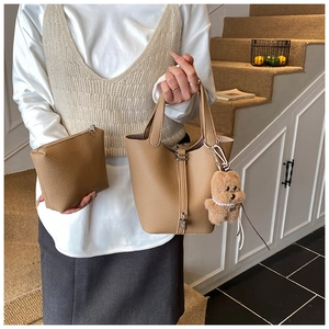 Detalle de bolso tipo cubo en cuero caqui con un lindo colgante de oso de peluche