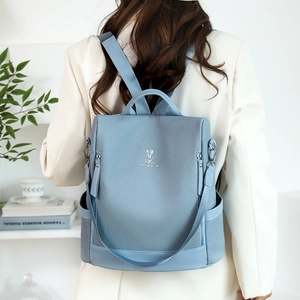 Detail of the light blue woven texture backpack with metal logo on a model's back