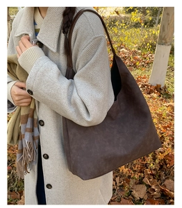 Detail of a dark brown hobo bag in matte texture styled with a grey autumn coat