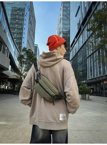Green ripstop chest bag with TENGRUN logo shown in a trendy urban street style setting